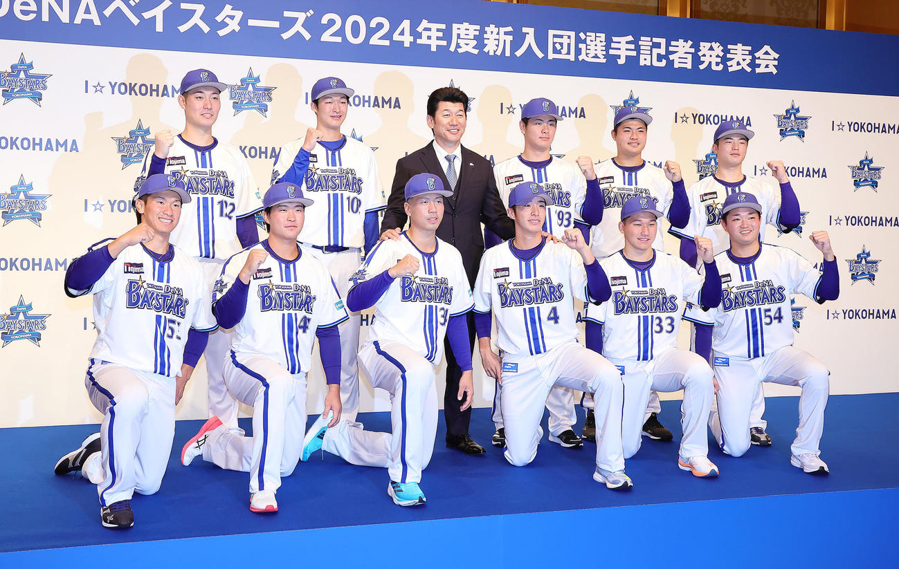 DeNA三浦監督（後方中央左）を囲み記念撮影に臨む新入団選手たち。前列左からドラフト6位井上、ドラフト4位石上、ドラフト2位松本、ドラフト1位度会、ドラフト3位武田、ドラフト5位石田、後列左から育成4位庄司、育成2位清水、1人おいて育成1位高見沢、育成3位小笠原、育成5位近藤（撮影・足立雅史）