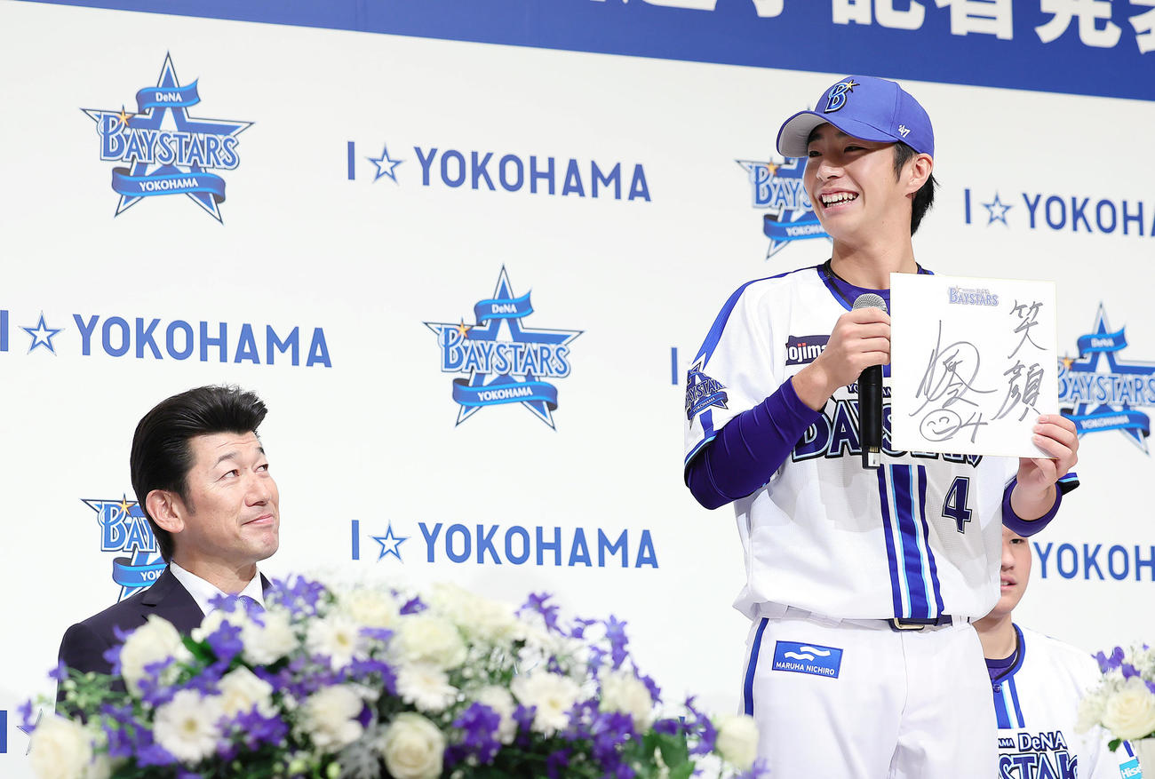 DeNA新入団選手発表会で抱負を話すドラフト1位の度会（右）を笑顔で見つめる三浦監督（撮影・足立雅史）