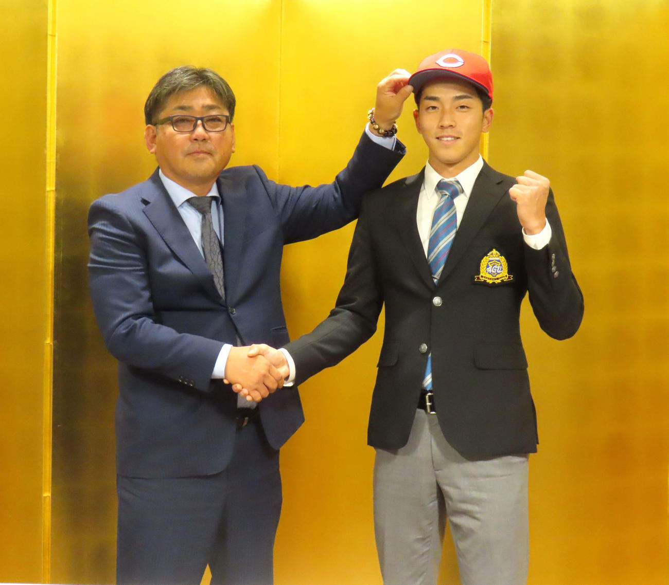 高山スカウト（左）と握手をし、ガッツポーズを決める広島1位　青学大・常広