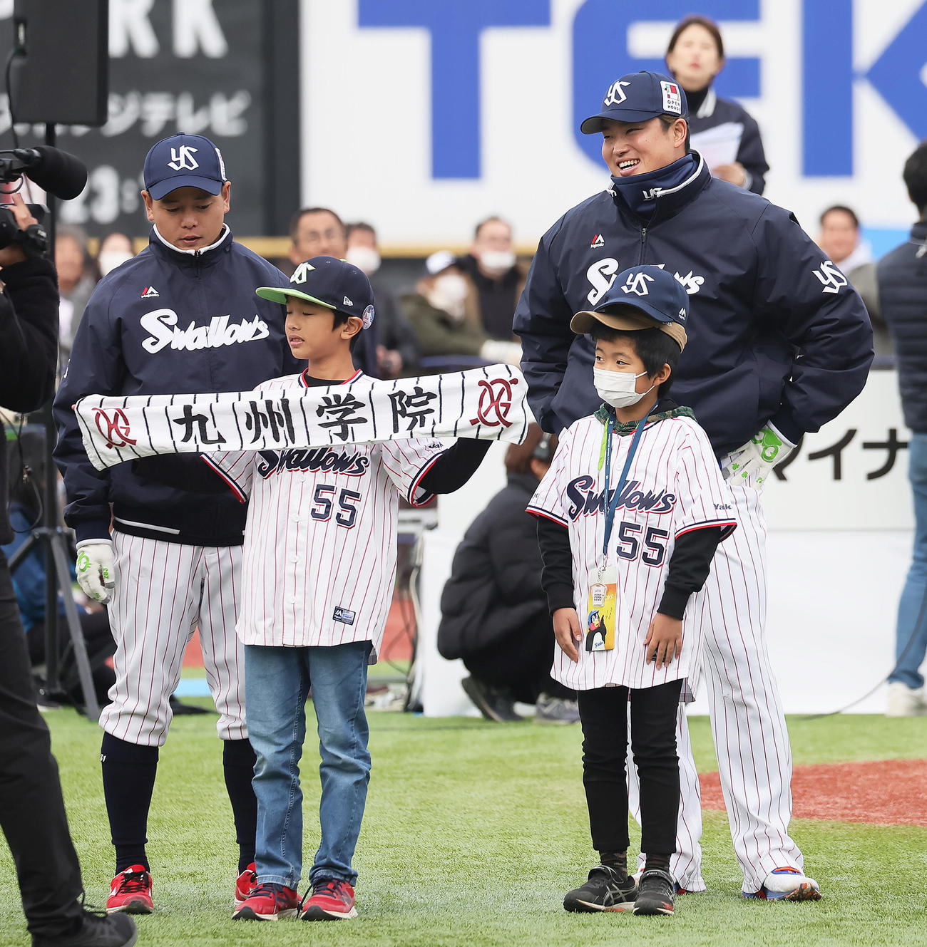 母校・九州学院高のタオルを手にしたファンに笑顔を見せるヤクルト村上（右）。左は山崎（撮影・足立雅史）