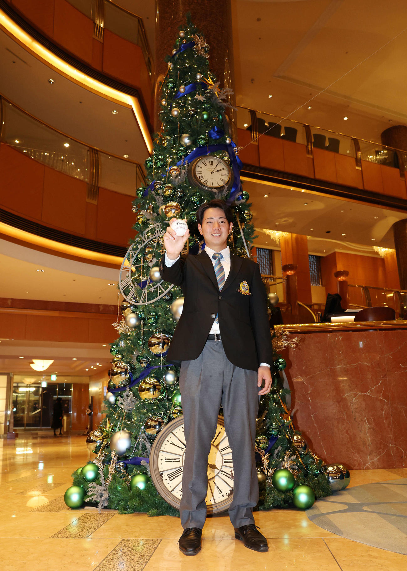 仮契約を終え、クリスマスツリーを背に笑顔を見せる阪神ドラフト1位の青学大・下村（撮影・宮地輝）