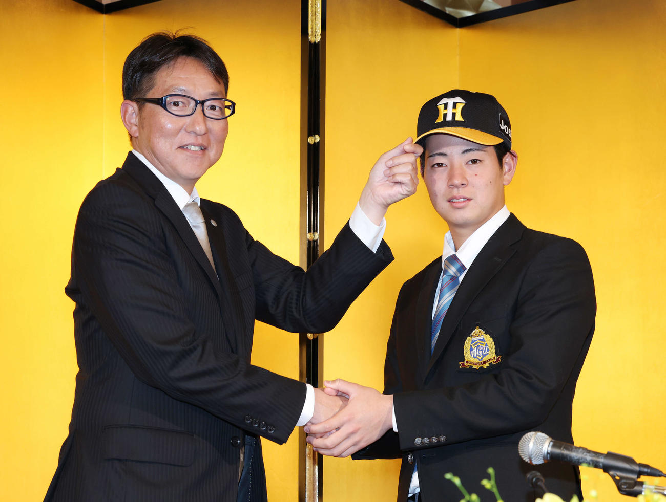 仮契約を終え、阪神吉野スカウト（左）と握手を交わすドラフト1位の青学大・下村（撮影・宮地輝）