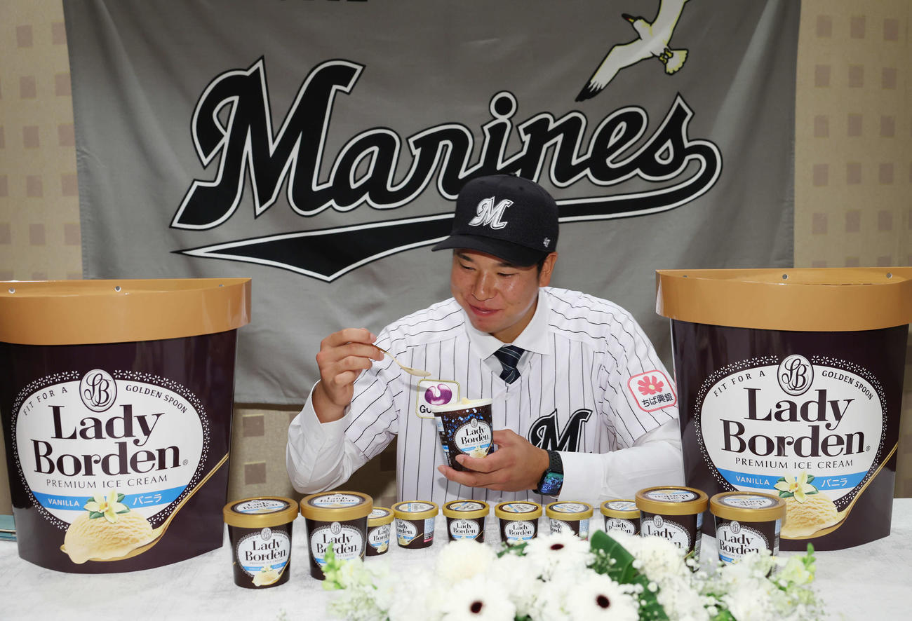契約を終え、大好きなロッテのアイスクリーム「レディーボーデン」をほおばり、笑顔を見せるロッテドラフト1位の明大・上田（撮影・宮地輝）