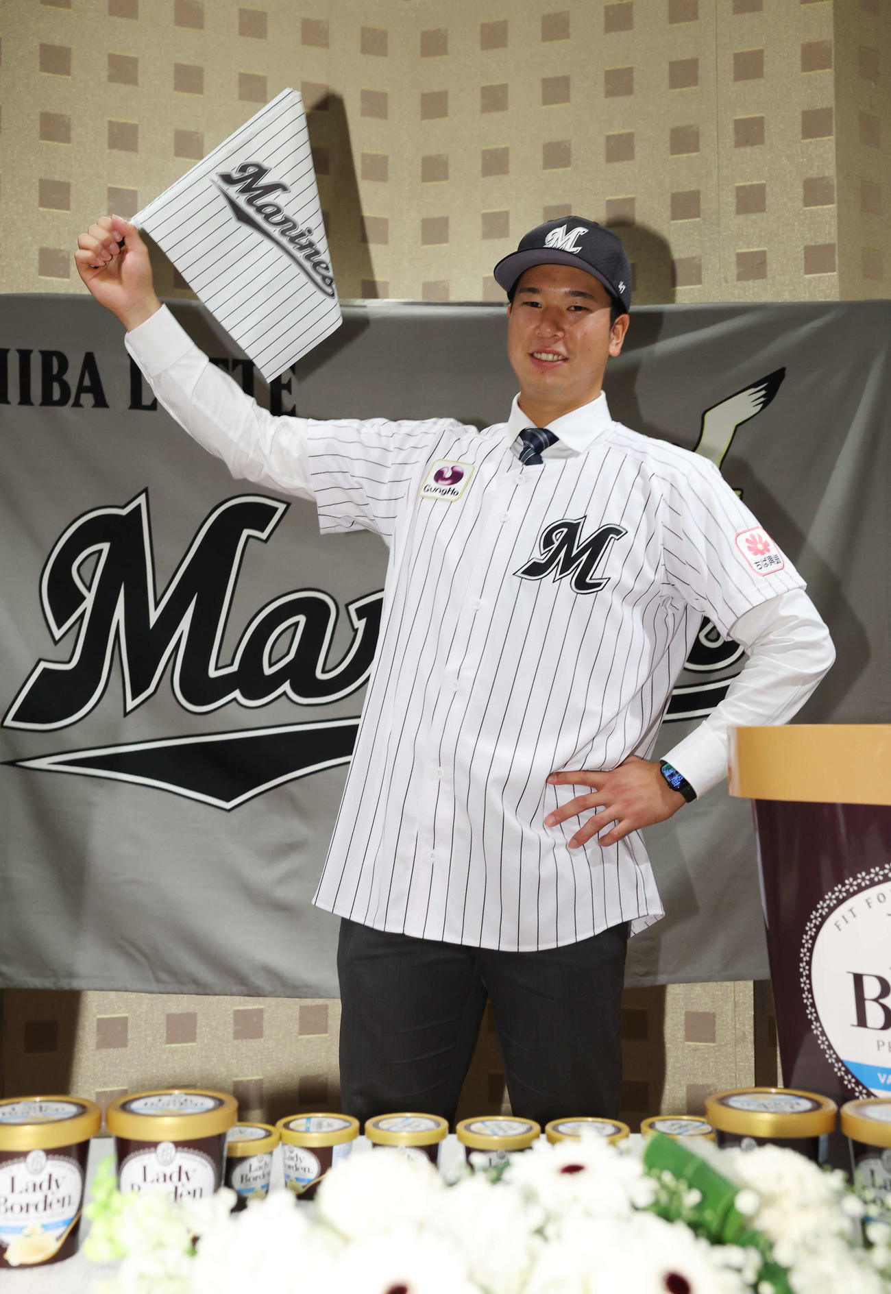 契約を終え、ロッテの旗を手に笑顔で武将ポーズを決めるドラフト1位の明大・上田（撮影・宮地輝）