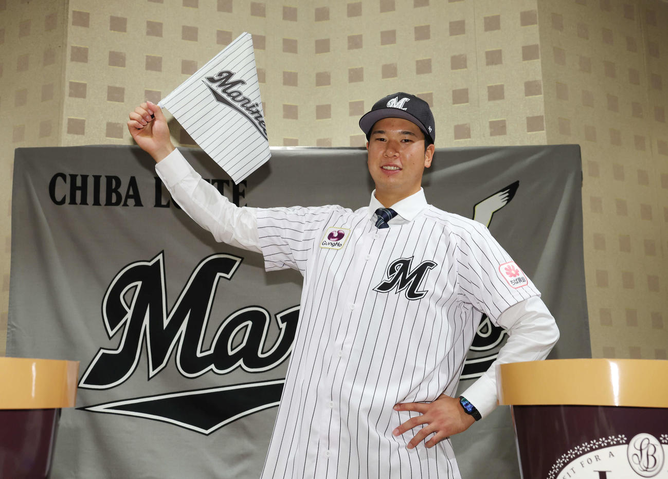 契約を終え、ロッテの旗を手に笑顔で武将ポーズを決めるドラフト1位の明大・上田（撮影・宮地輝）