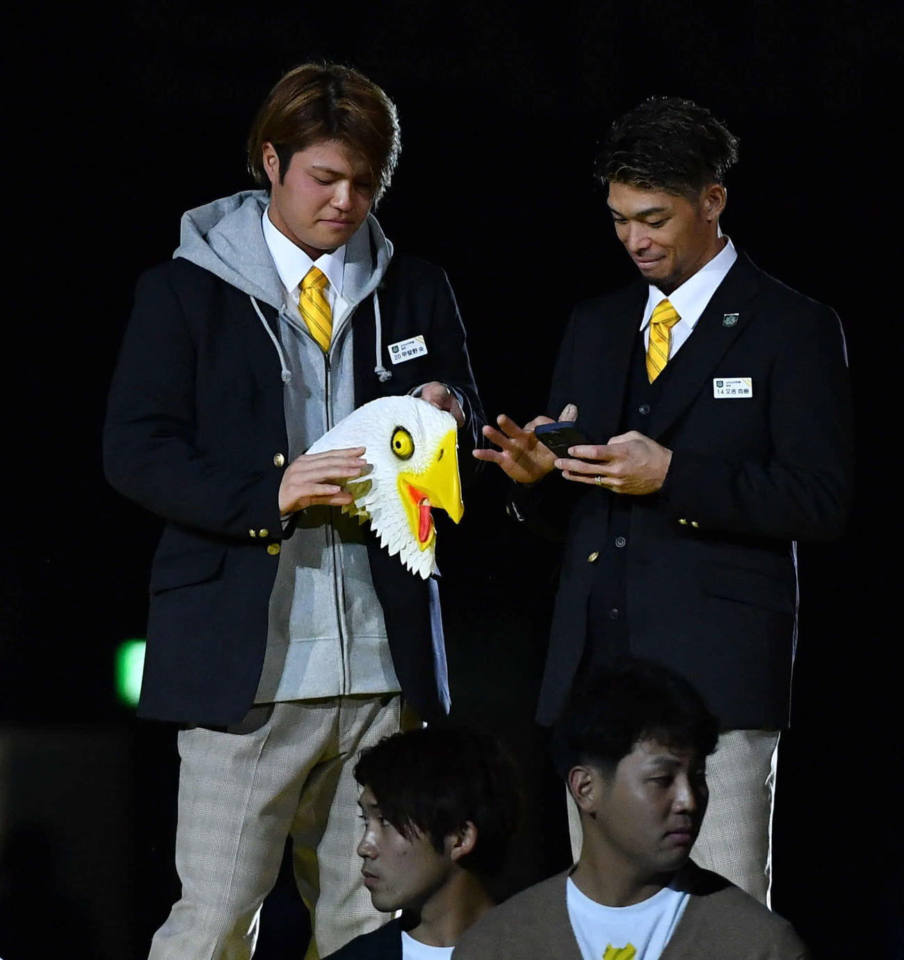 ファンフェスティバルの開会式で鳥のかぶりものを手にする甲斐野（左）。右は又吉（撮影・岩下翔太）