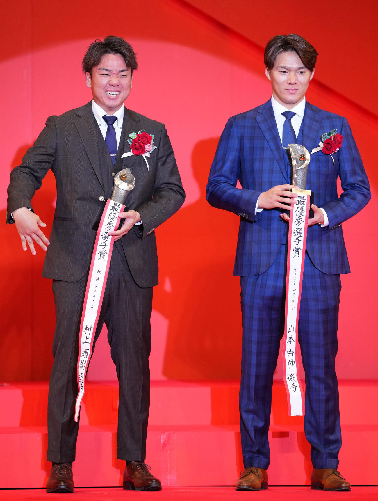 トロフィー2個持ちは重たかったらしくつらい表情を見せる阪神村上。右はオリックス山本（撮影・横山健太）