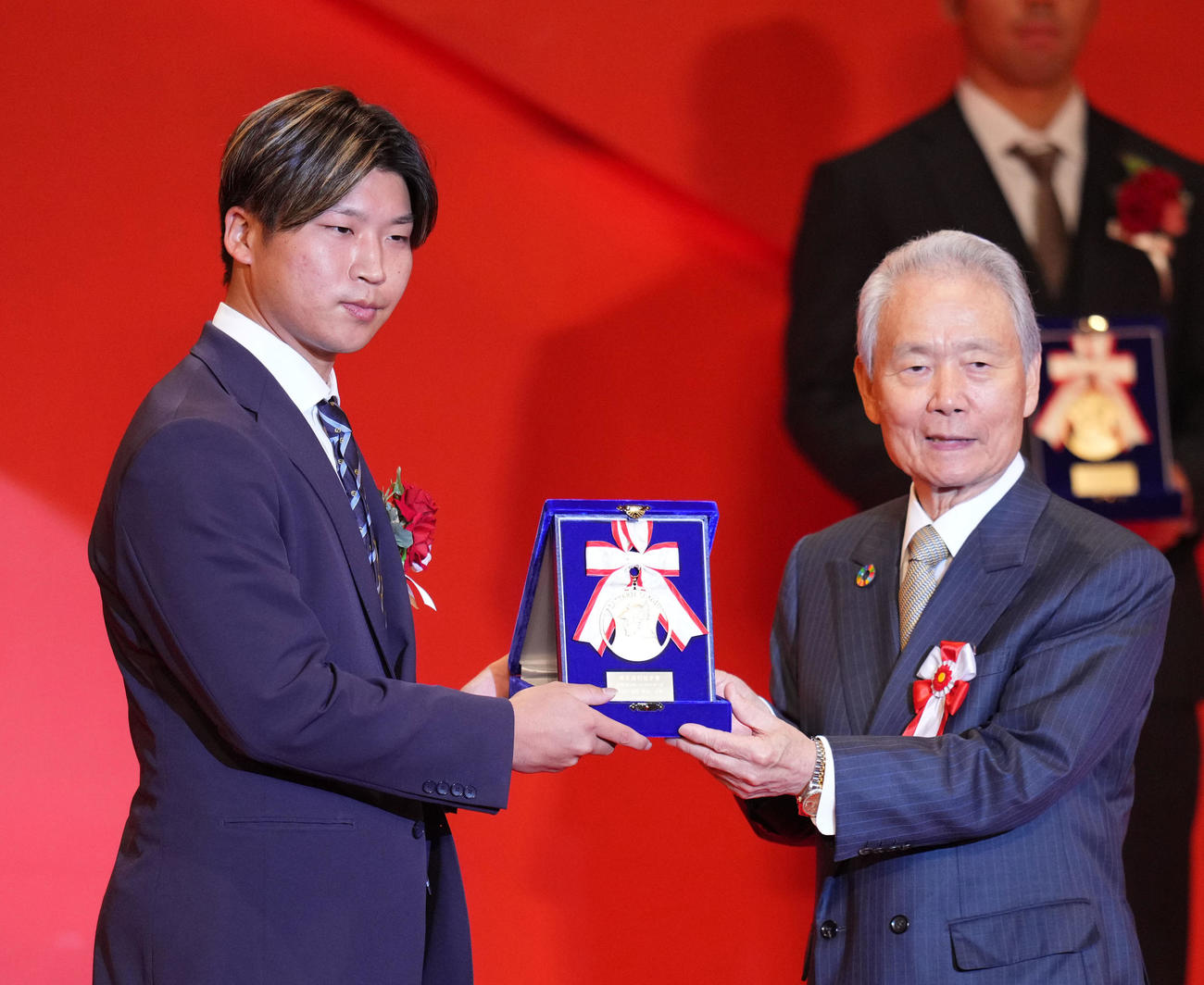 イースタン・リーグ最多勝利投手賞を受賞した日本ハム長谷川。右は榊原コミッショナー（撮影・横山健太）