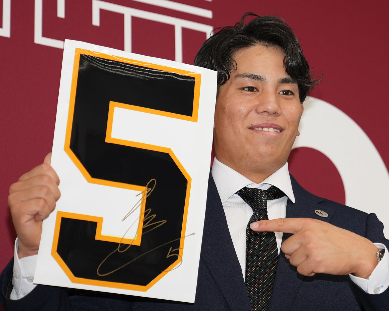 契約更改後、来季背番号「5」を手に笑顔を見せる巨人門脇（撮影・狩俣裕三）