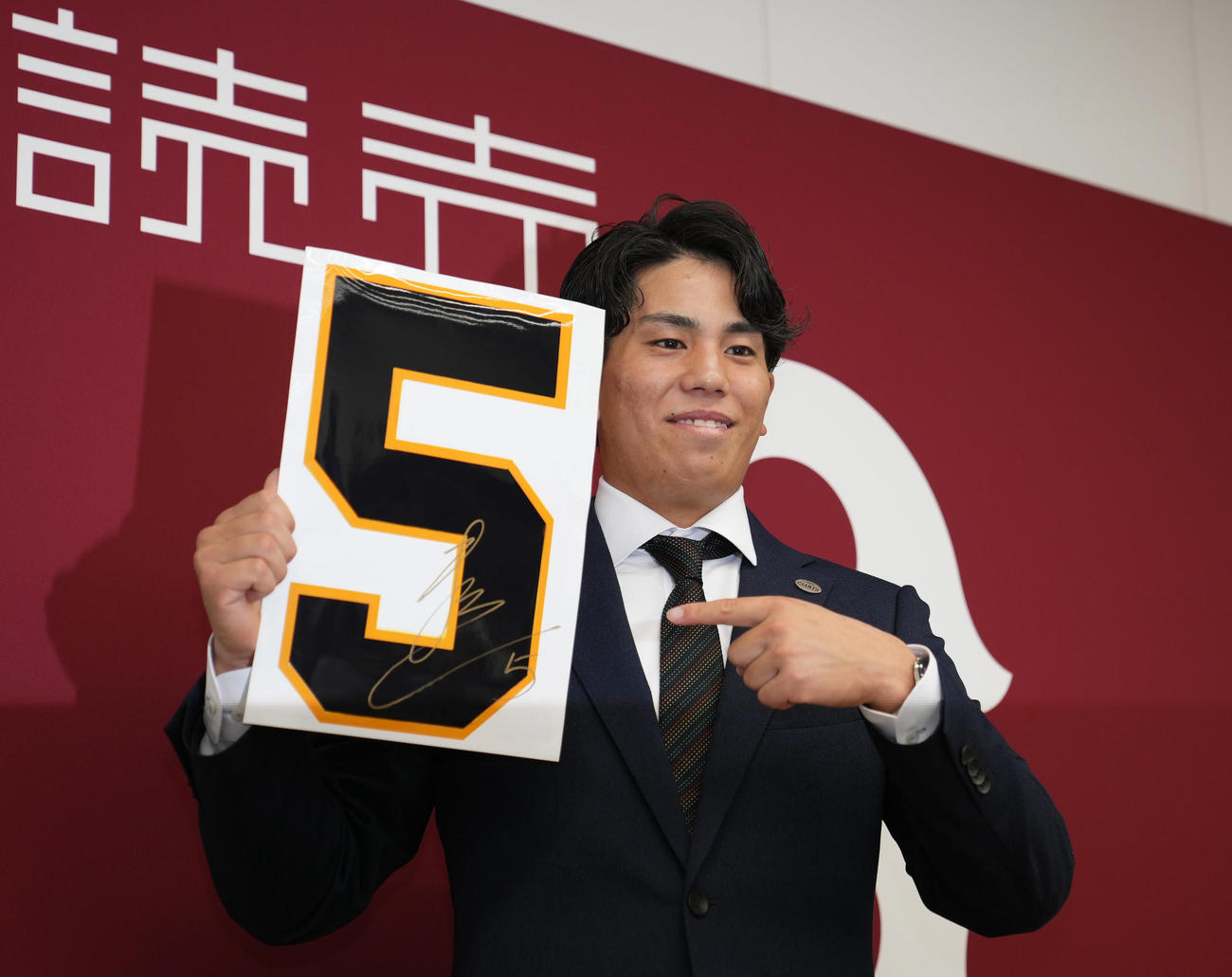 契約更改後、来季背番号「5」を手に笑顔を見せる巨人門脇（撮影・狩俣裕三）