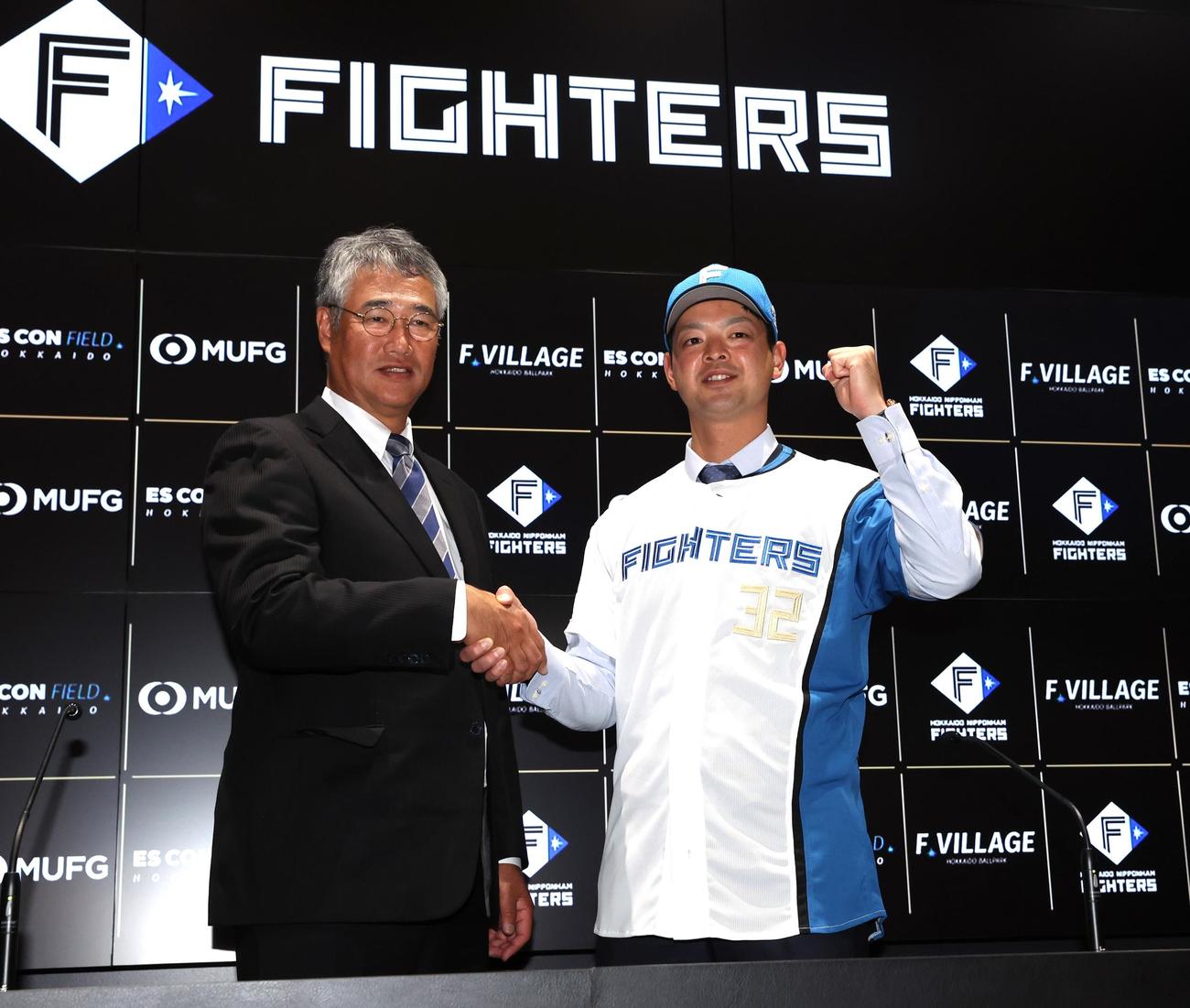 日本ハムへの移籍会見で木田GM代行（左）と握手する黒木（撮影・黒川智章）