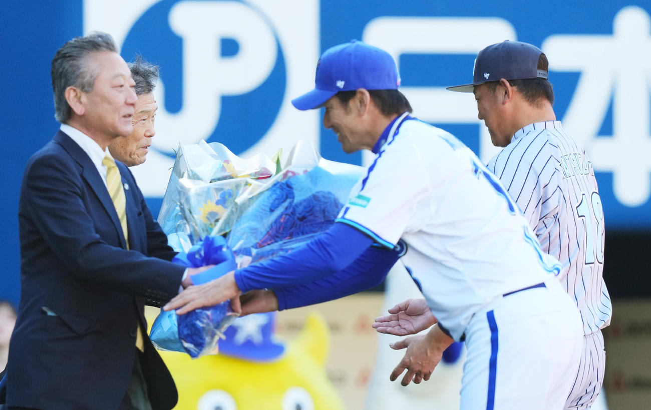 オープニングセレモニーで横浜・渡辺元監督（左から2人目）から花束を受け取り、笑顔を見せる松坂氏。前方右は三浦監督（撮影・菅敏）