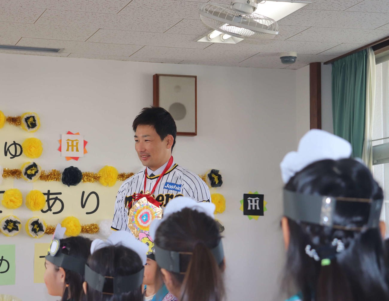 玩具の寄贈式で園児らから手作りの金メダルを送られた阪神岩崎優投手（撮影・波部俊之介）