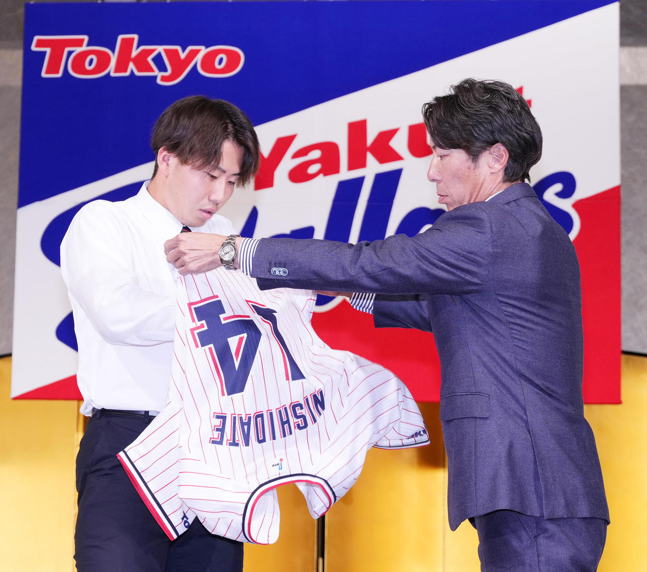 ヤクルト新入団選手発表会で高津監督（右）からユニホームを着させてもらうドラフト1位の西舘（撮影・菅敏）