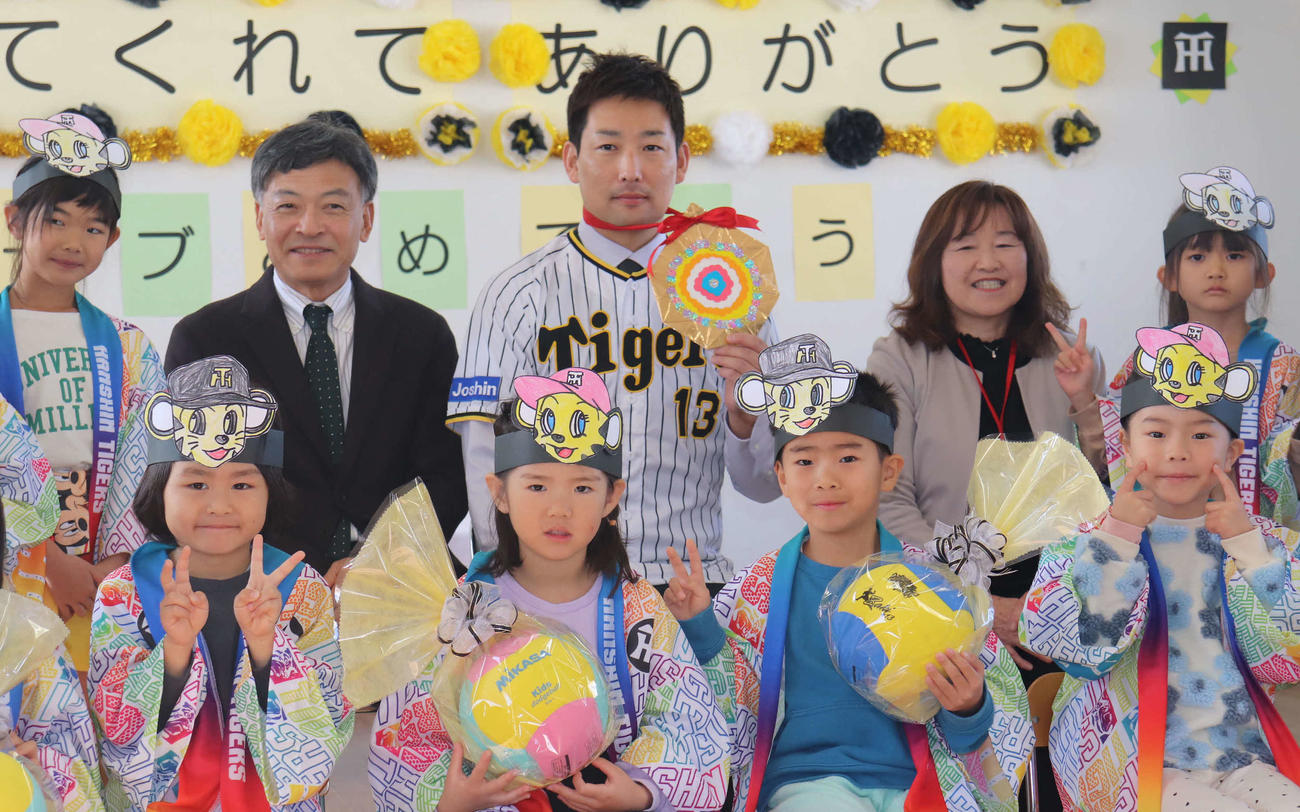 園児らからの手作り金メダルを手に、記念撮影する阪神岩崎（後列中央）（撮影・波部俊之介）