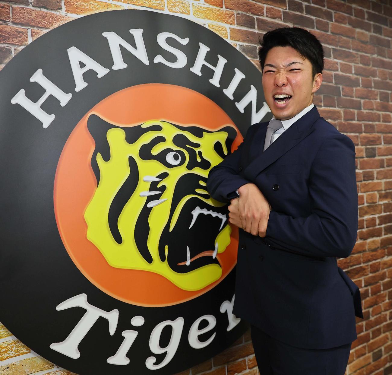契約更改した石井は気合の表情でマッスルポーズを決める（撮影・上田博志）