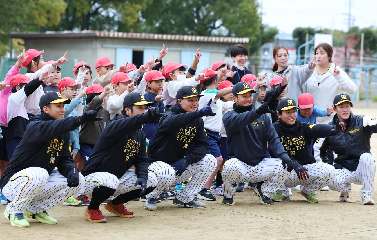 ゲストティーチャーで小学校を訪れ、生徒たちと笑顔で集合写真に納まる阪神の選手たち。手前左から、茨木、井坪、森下、門別、戸井、富田（撮影・前田充）
