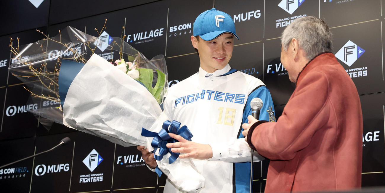入団会見で日本ハム山崎（左）は沢村豊医師から花束を手渡される（撮影・佐藤翔太）