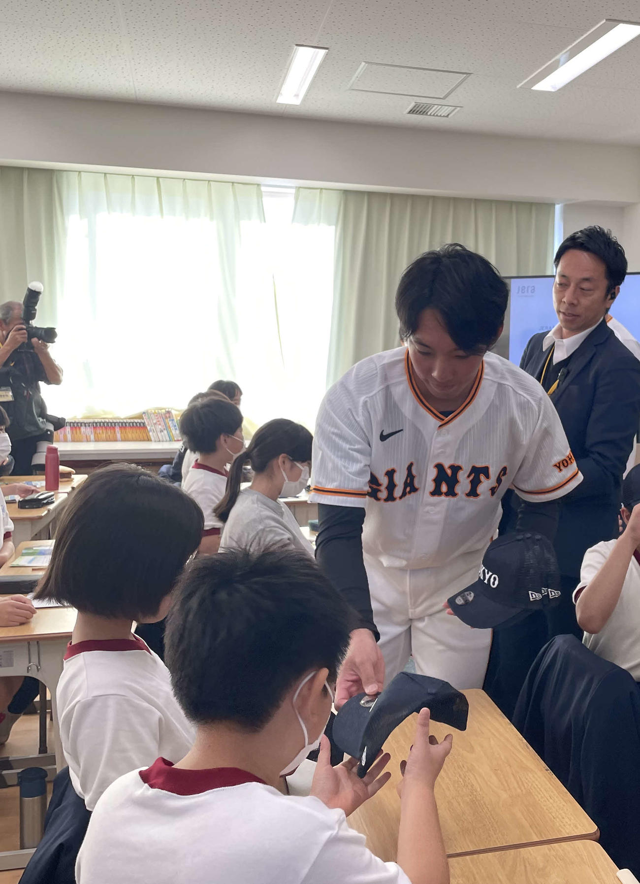 子どもらに帽子を配る人赤星