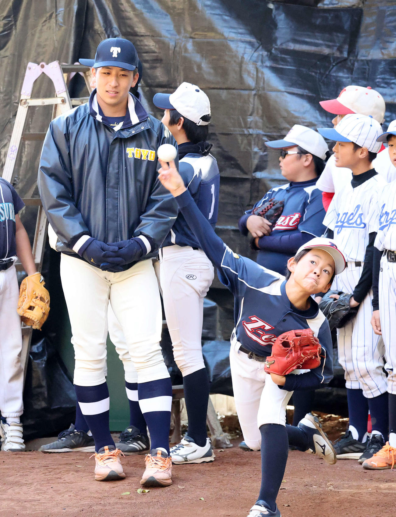 ブルペンで子供たちの投球を見つめる日本ハムドラフト1位の東洋大・細野（撮影・鈴木正人）