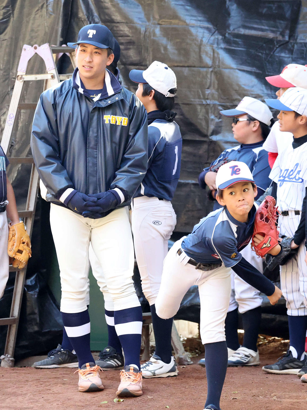 ブルペンで子供たちの投球を見つめる日本ハムドラフト1位の東洋大・細野（撮影・鈴木正人）