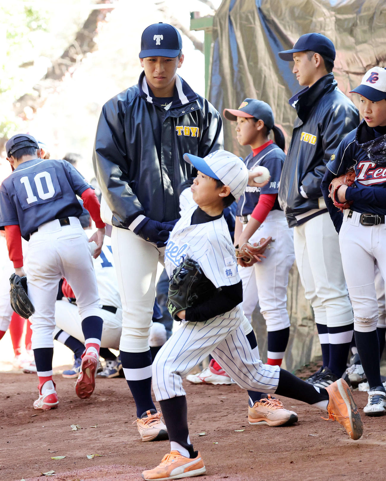 ブルペンで子供たちの投球を見つめる日本ハムドラフト1位の東洋大・細野（撮影・鈴木正人）