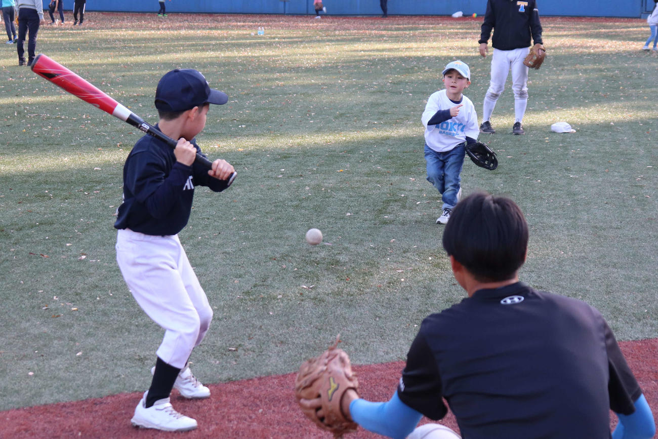 東京6大学野球の社会連携アクション、「野球部グランドを子どもたちの遊び場へ」でグラウンドを開放し、チームが用意したプラスチックのバットとゴムボールで部員と遊ぶ子どもたち（撮影・保坂淑子）