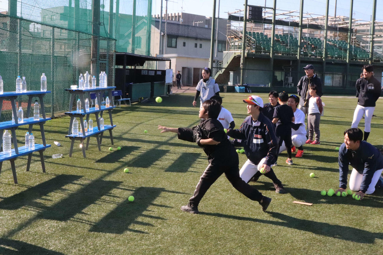 東京6大学野球の社会連携アクション、「野球部グランドを子どもたちの遊び場へ」で、水を入れたペットボトルを的に、ボール当てゲーム感覚で遊ぶ子どもたち（撮影・保坂淑子）