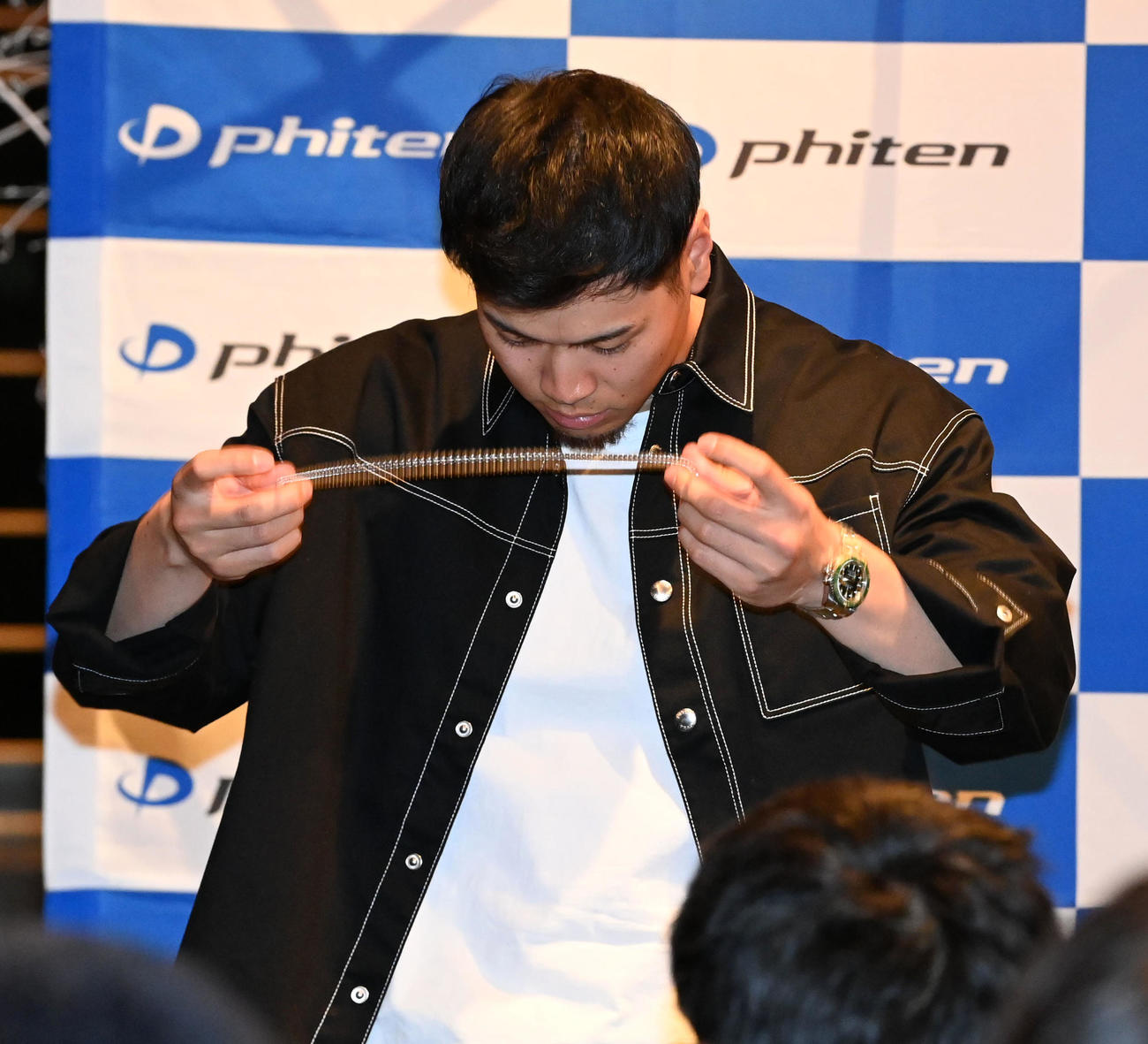 ファンミーティングの抽選会で、プレゼントのため身につけていたネックレスを外す佐藤輝（撮影・前岡正明）
