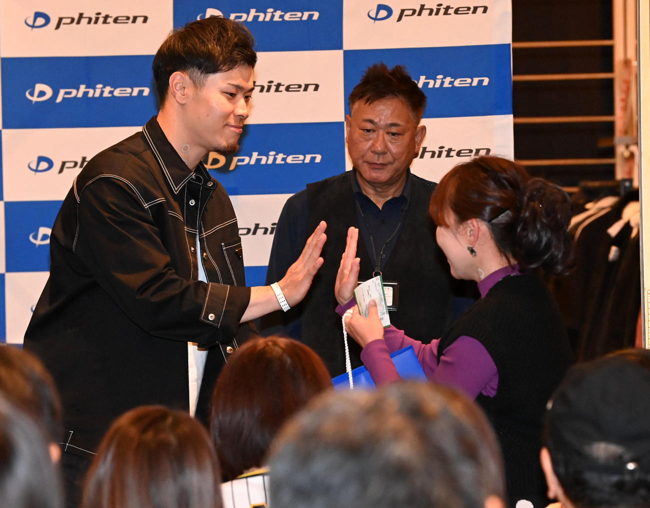 ファンミーティングの抽選会でファンにプレゼントを手渡す佐藤輝（撮影・前岡正明）