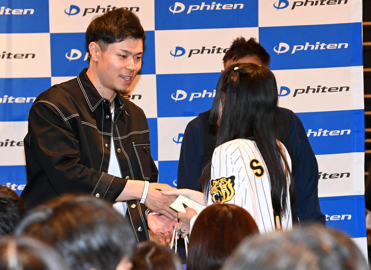 ファンミーティングの抽選会でファンにプレゼントを手渡す佐藤輝（撮影・前岡正明）