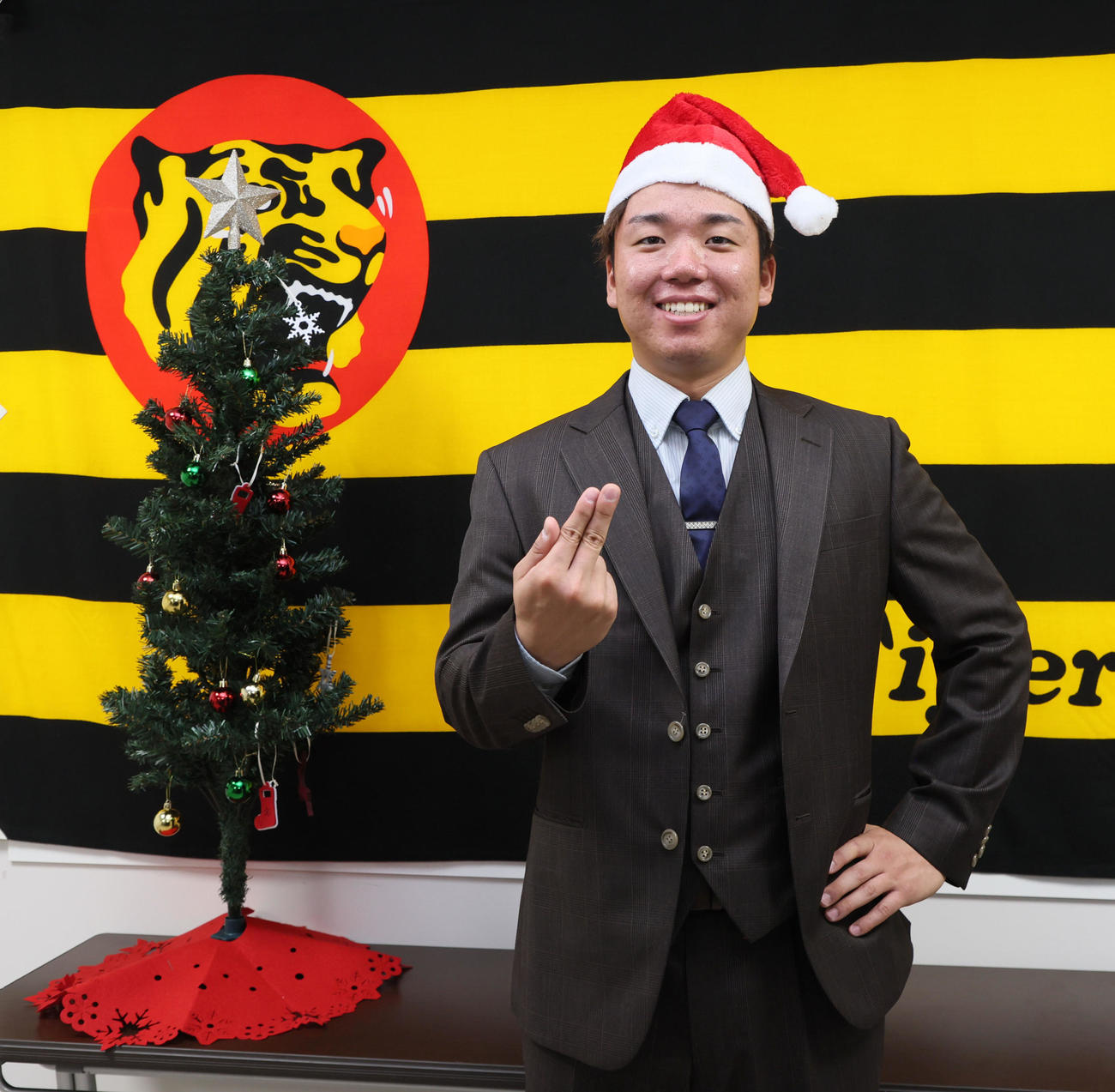 球団史上最高となるアップ率で契約を更改しサンタの帽子をかぶって淡路島ポーズを見せる村上（撮影・加藤哉）