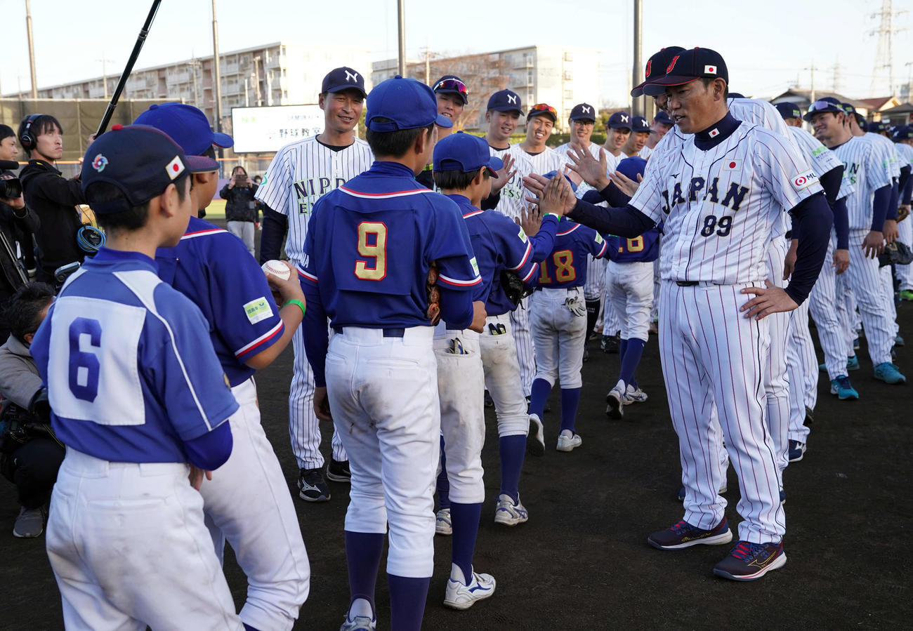 子どもたちとハイタッチをする侍ジャパン井端監督。左は日本通運沢村監督（撮影・たえ見朱実）