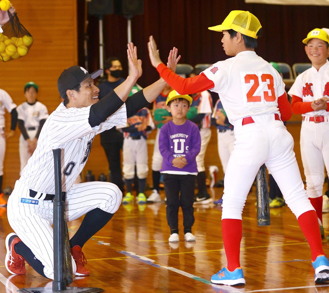 奈良県人会の野球教室で子供とハイタッチするロッテ荻野（撮影・上山淳一）