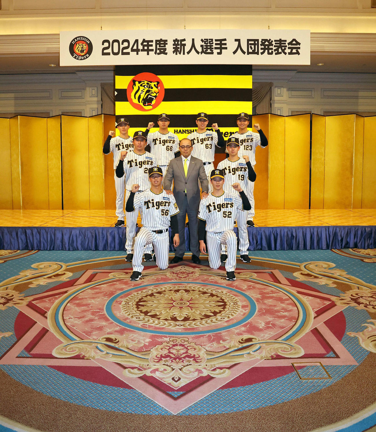 ガッツポーズで笑顔を見せる2024年度阪神新入団選手、下段左からドラフト4位百崎、ドラフト3位山田、中段左からドラフト2位椎葉、岡田監督、ドラフト1位下村、上段左から育成ドラフト2位福島、ドラフト6位津田、ドラフト5位石黒、育成ドラフト1位松原（撮影・上田博志）