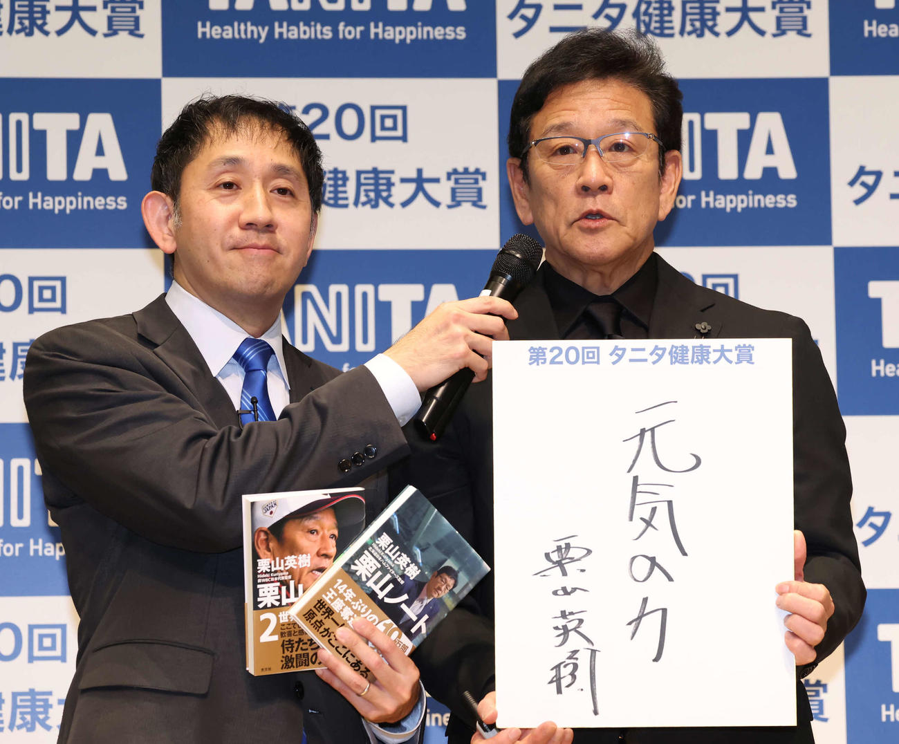 来年のテーマを「元気の力」と記した栗山氏（右）。左はタニタの谷田社長（撮影・丹羽敏通）