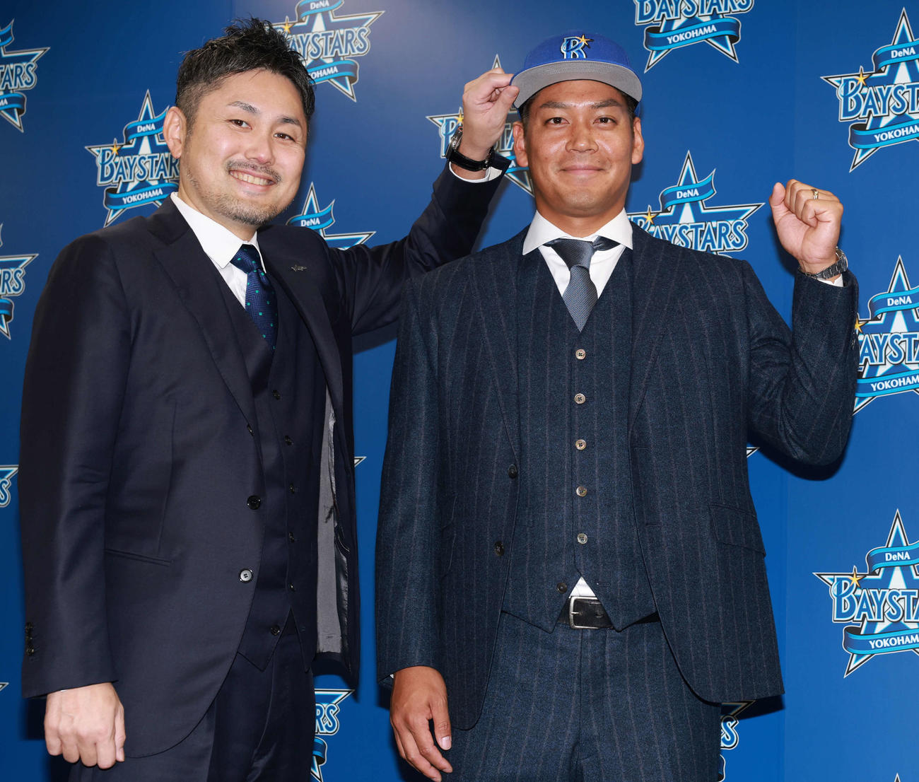 入団会見で萩原チーム統括本部長（左）から帽子をかぶせられるDeNA佐々木（撮影・野上伸悟）
