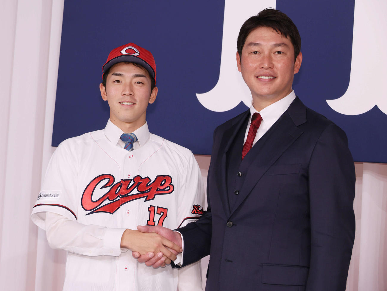新井監督（右）と握手するドラフト1位の常広（撮影・加藤孝規）
