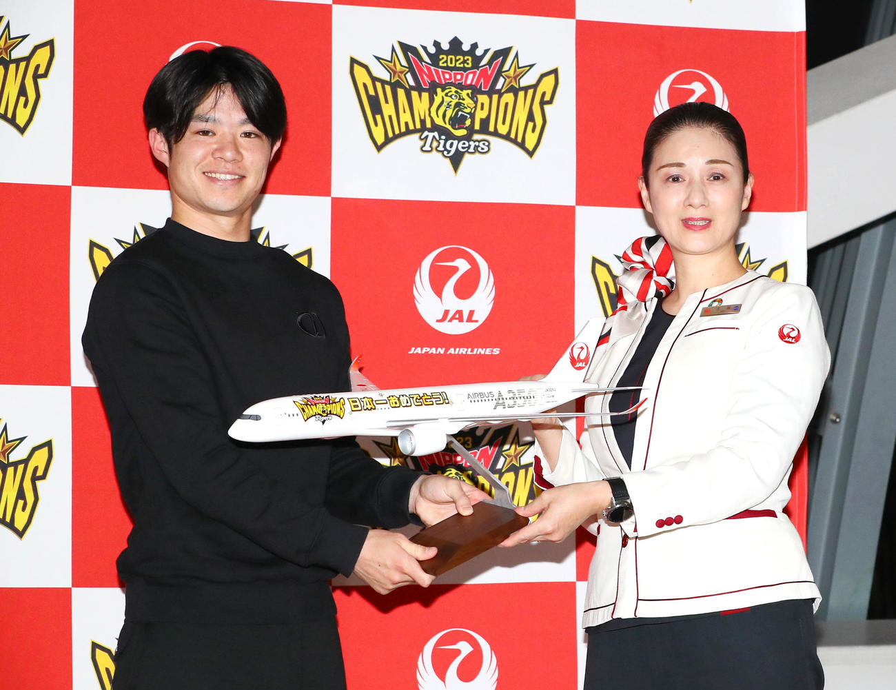 V旅行出発式で阪神中野（左）はモデルの飛行機を贈られ笑顔を見せる（撮影・上山淳一）