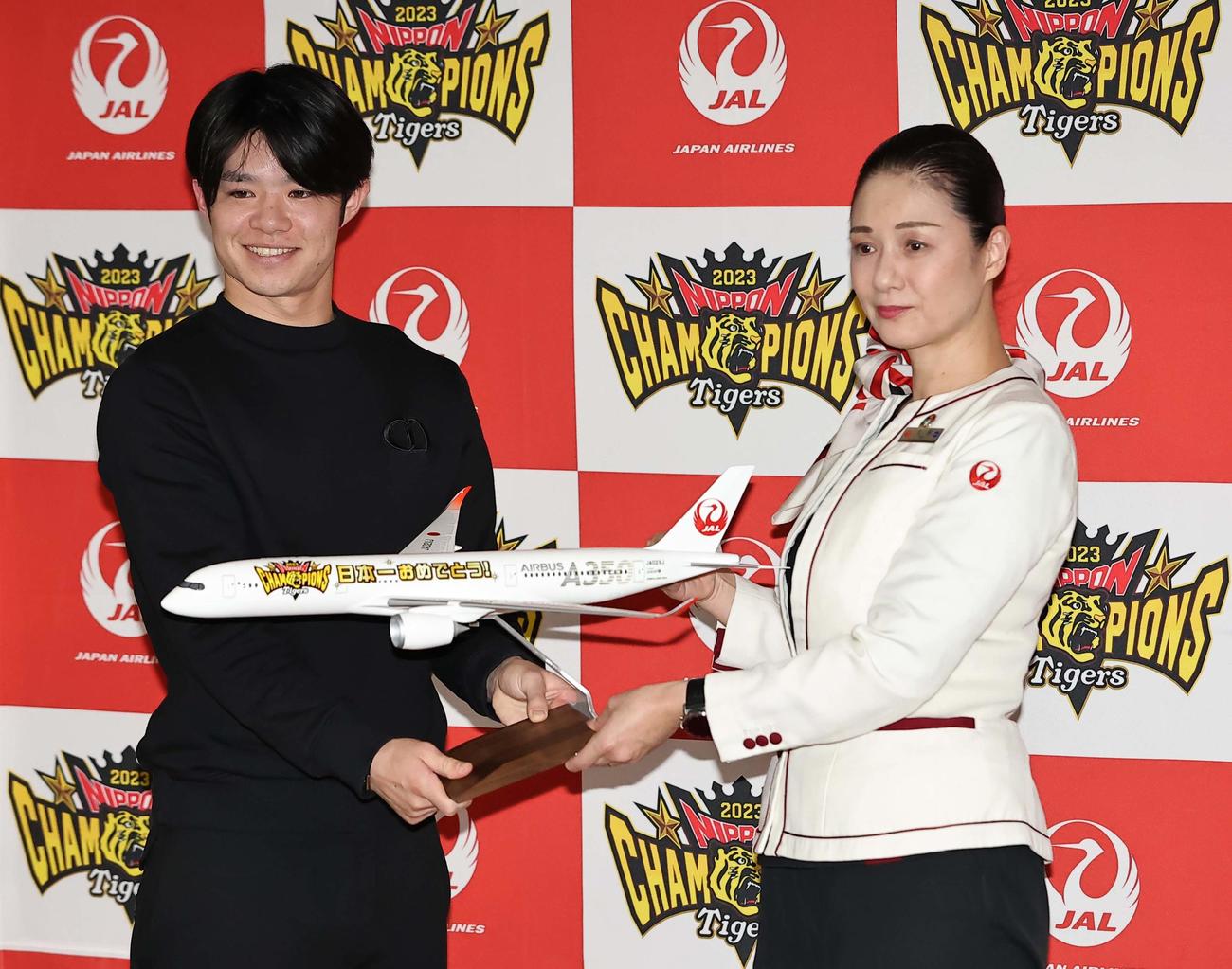 V旅行に出発する中野（左）は客室乗務員の土居さんからモデルプレーンを受け取り笑顔を見せる（撮影・上田博志）