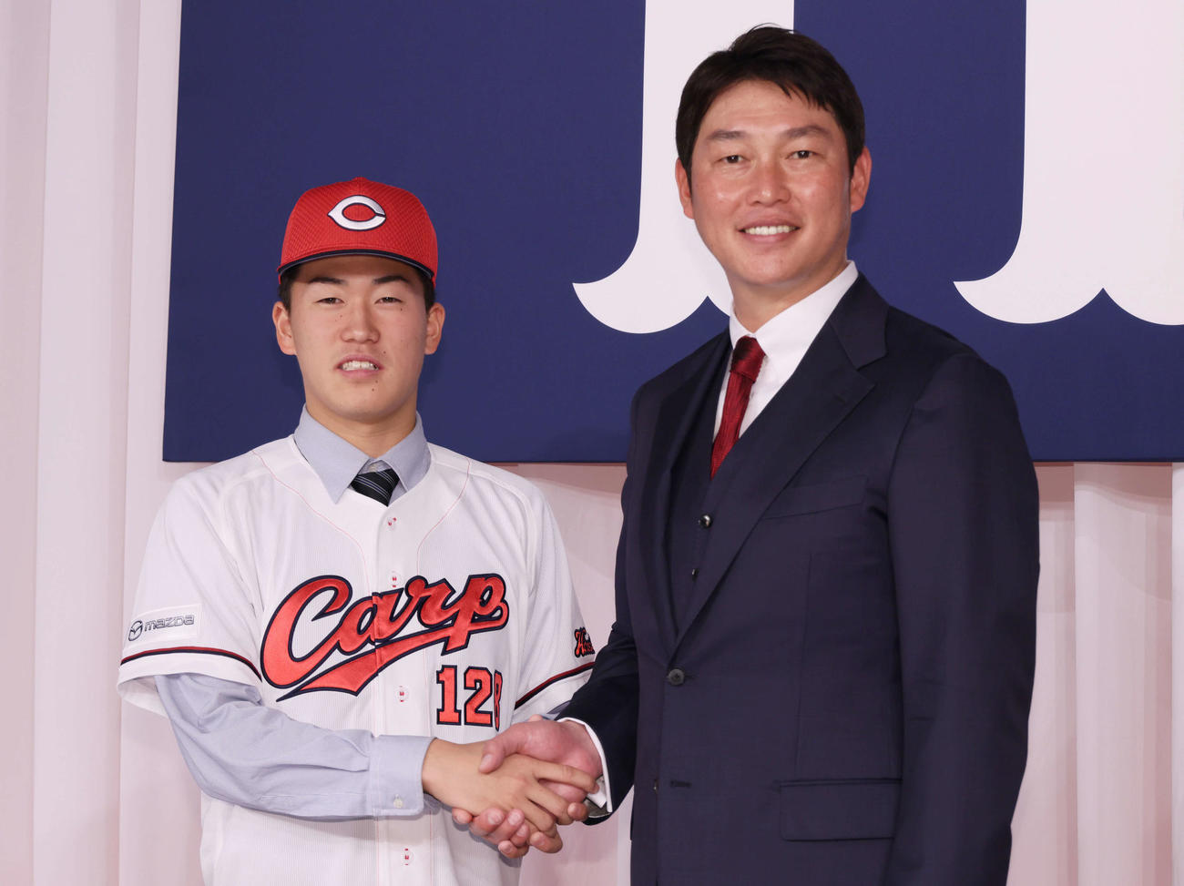 広島新入団選手会見　新井監督（右）と握手する育成3位の杉原（撮影・加藤孝規）