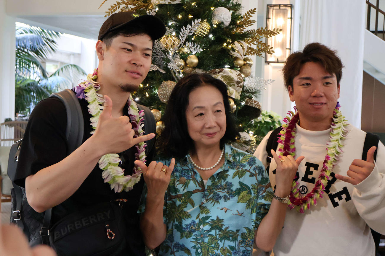宿泊先のホテルで関係者と記念撮影に応じる阪神佐藤輝（左）と村上（撮影・古財稜明）