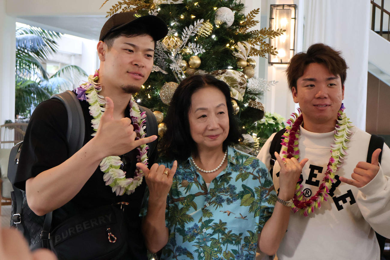 宿泊先のホテルで関係者と記念撮影に応じる佐藤輝（左）と村上（撮影・古財稜明）