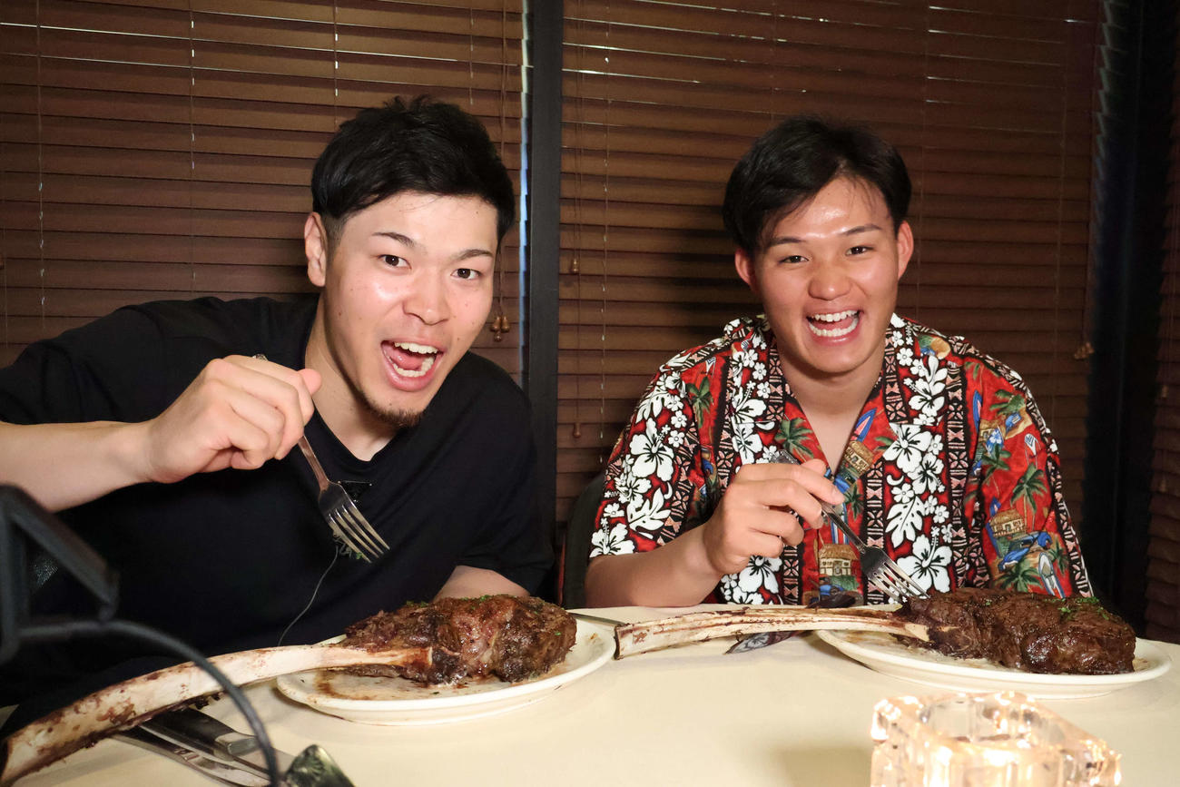 ハワイのステーキ店で骨付きステーキを前に興奮する阪神佐藤輝（左）と森下（撮影・古財稜明）