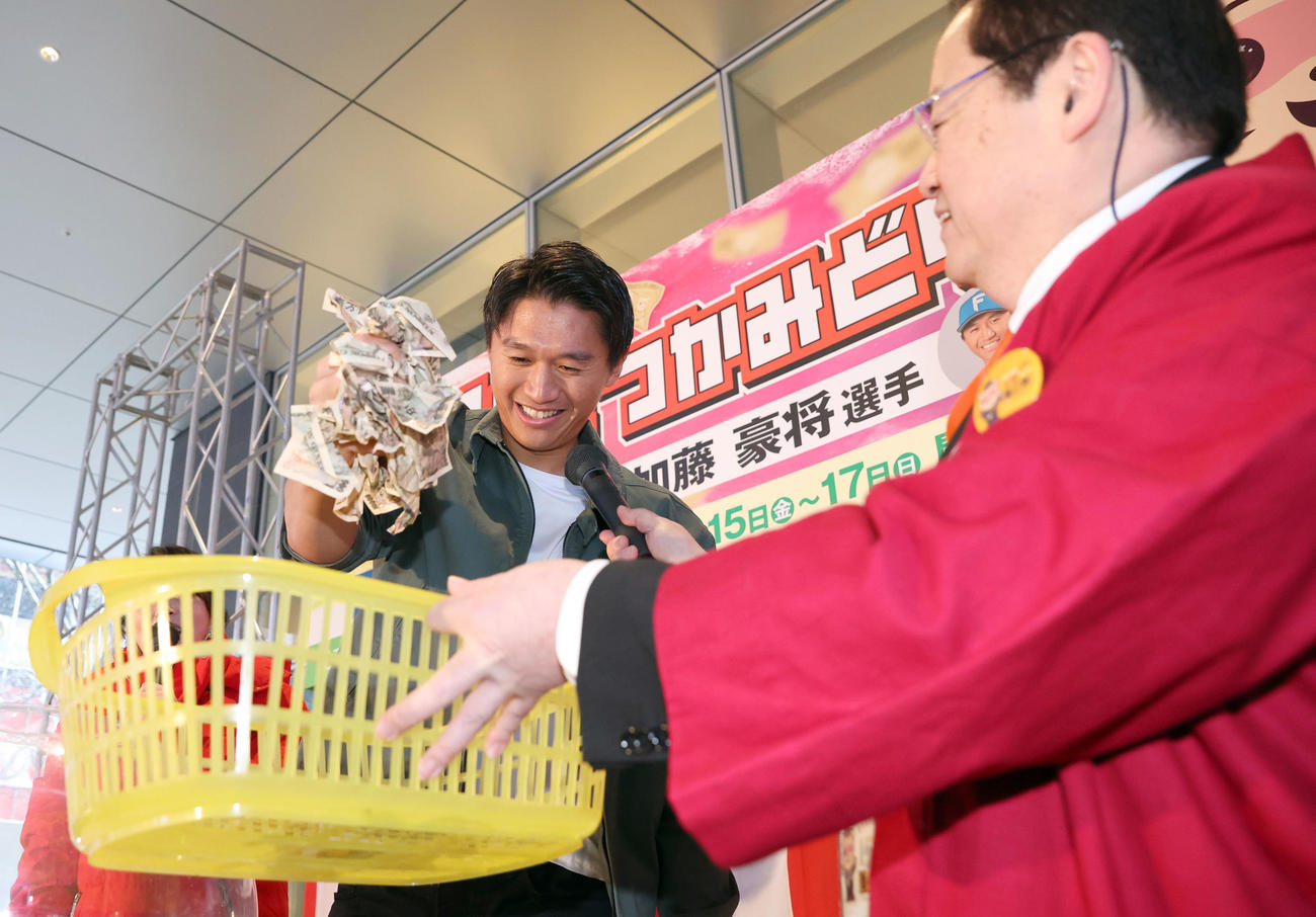 狸小路商店街で行われた「現金つかみ取り」に参加した日本ハム加藤豪はたくさんの1万円札を鷲づかみにし笑顔を見せる（撮影・佐藤翔太）