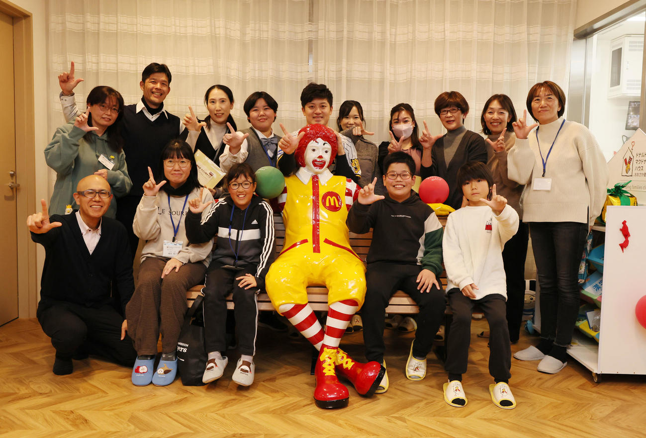施設を訪問し利用者家族らと記念写真に納まる坂本（撮影・加藤哉）