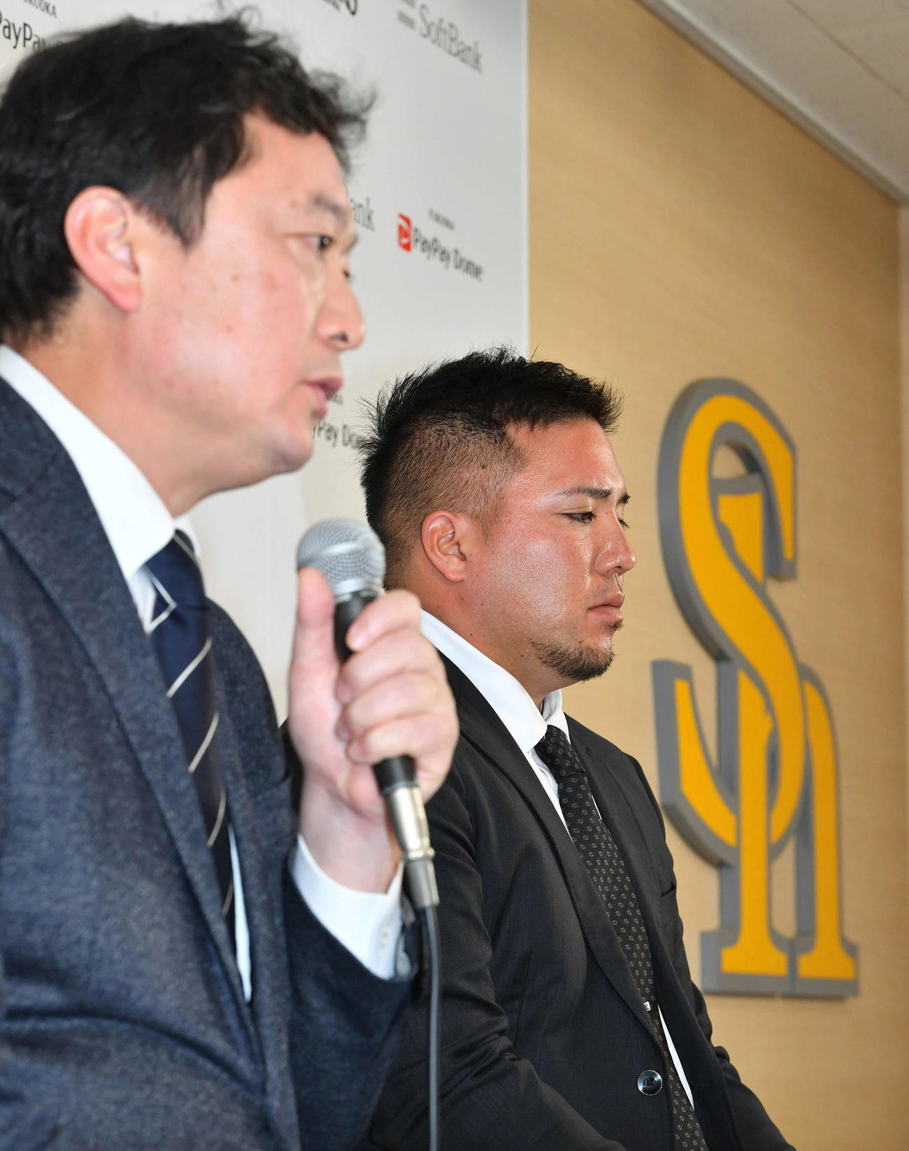 ソフトバンクへの入団会見で、三笠GM（左）の話す間に厳しい表情を見せる山川（撮影・岩下翔太）