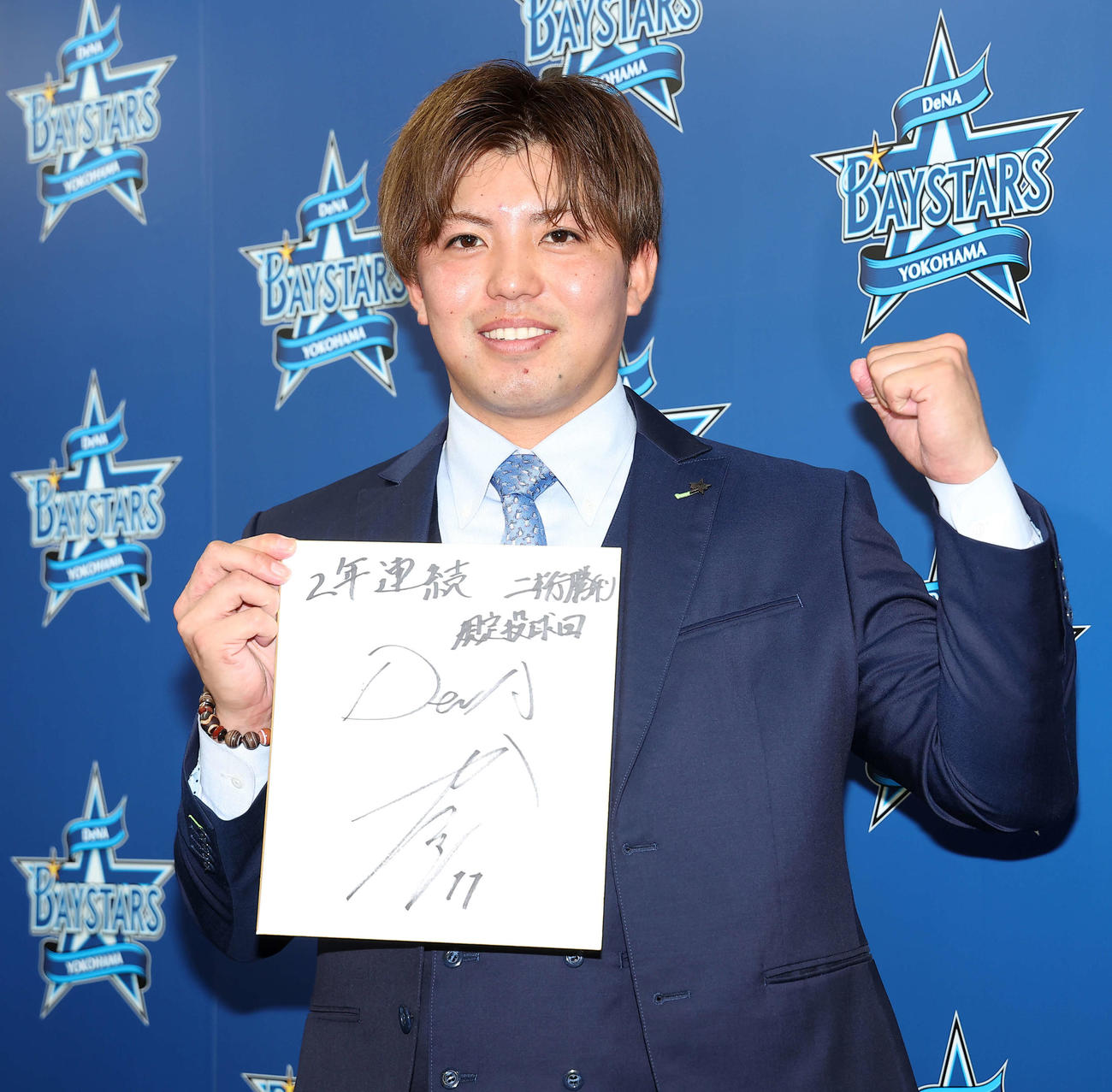 契約更改後、「2年連続二桁勝利、規定投球回」としたためた色紙を手に写真に納まるDeNA東（撮影・河田真司）