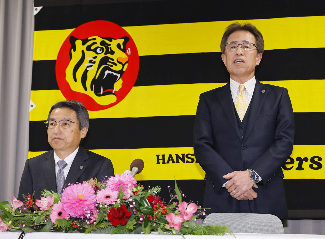 阪神の次期球団社長に決まり、記者会見であいさつする粟井副社長。左は百北球団社長（撮影・藤尾明華）