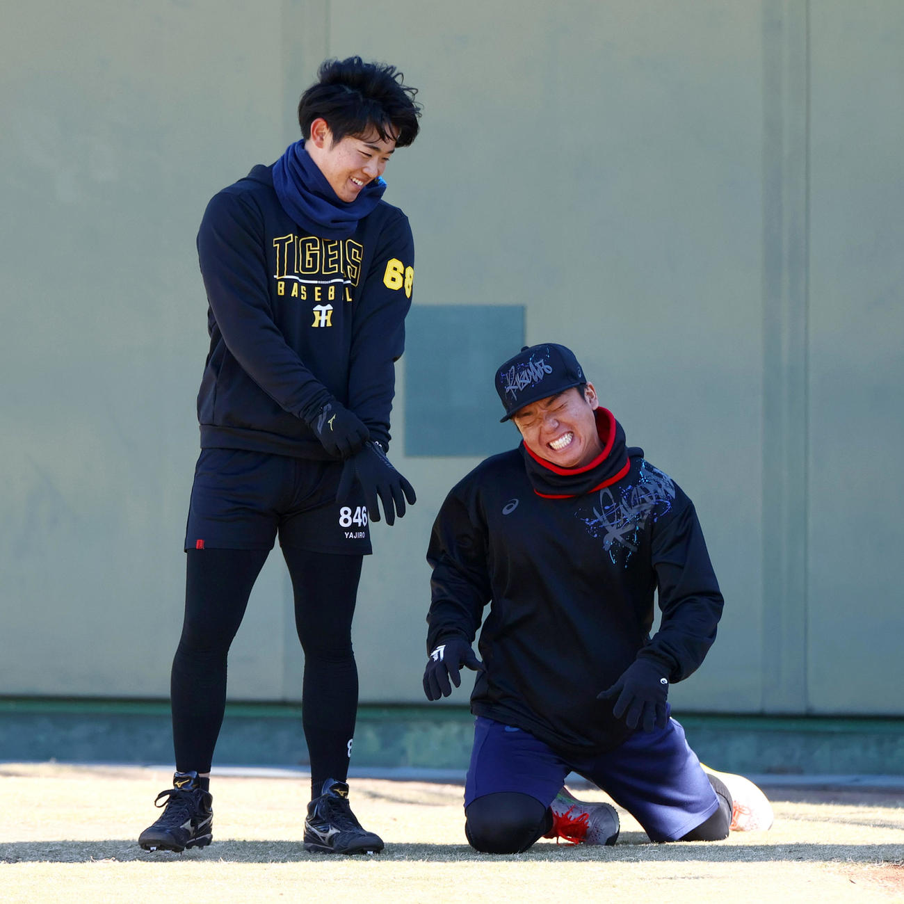 鳴尾浜球場で自主トレの阪神村上（右）は阪神中川に足を負傷したふりをする（撮影・上山淳一）